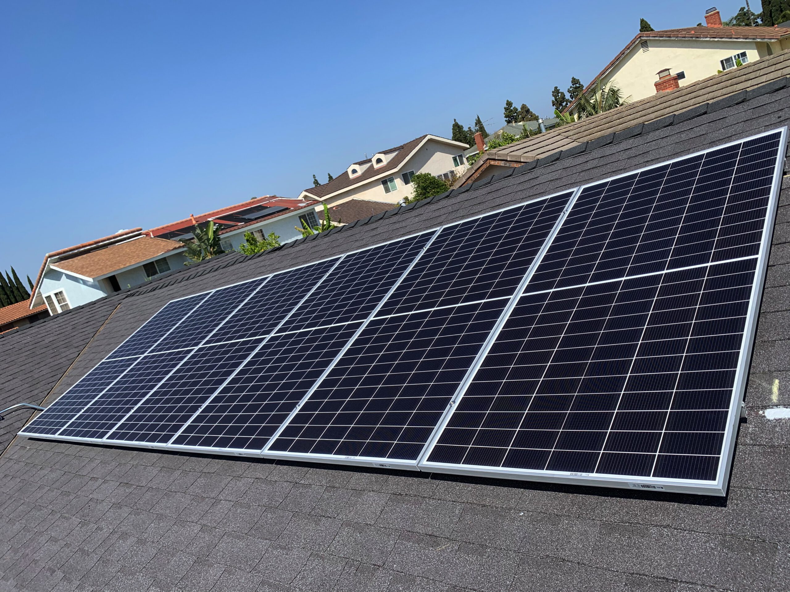 Solar panel installation on a Fountain Valley home roof by AMECO Solar & Roofing under a clear blue…