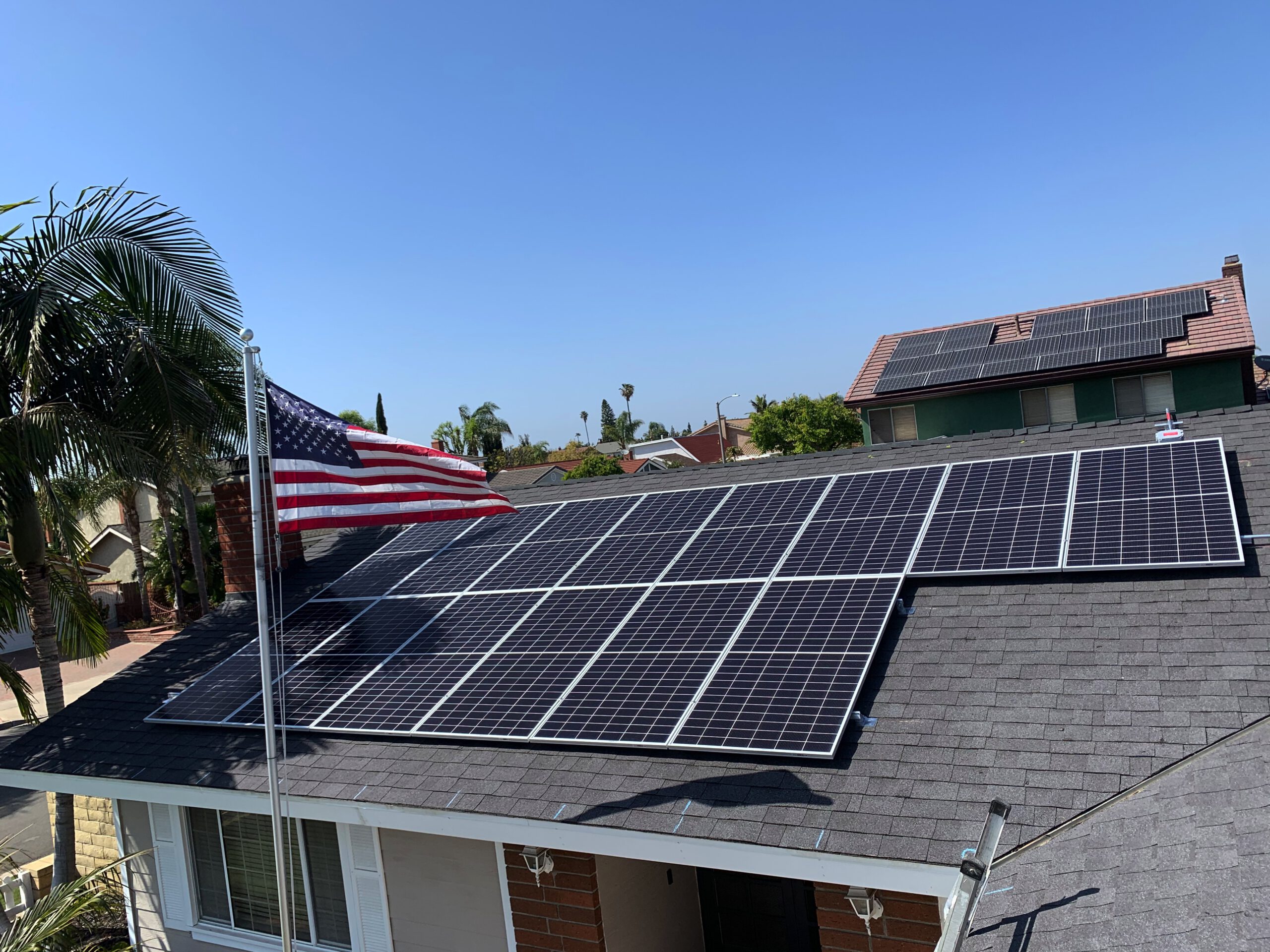 Solar panel installation on a Fountain Valley home with an American flag, featuring AMECO Solar & Ro…
